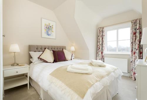a bedroom with a white bed with a window at Upper End House in Shipton under Wychwood