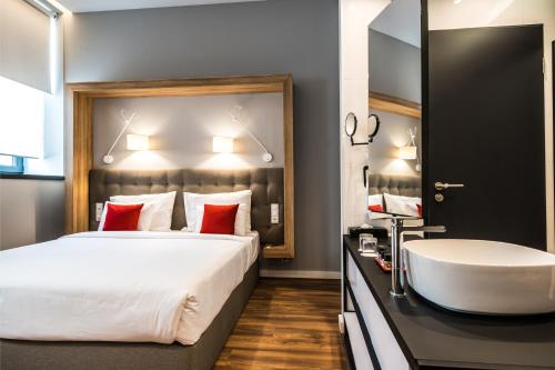 a bedroom with a tub and a bed and a sink at Up Hotel Budapest in Budapest