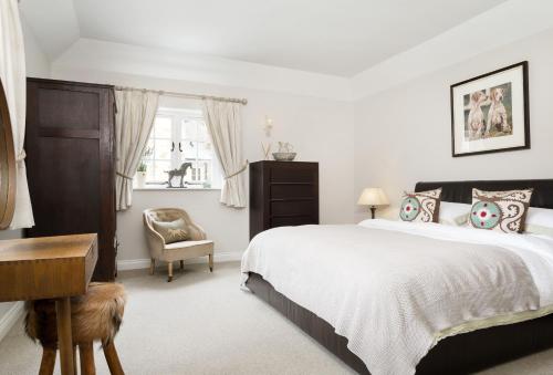Un dormitorio con una cama, un escritorio y una silla. en Grooms Cottage, en Kingham