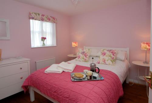 a bedroom with a bed with a tray of food on it at Little Shrublands in Blockley