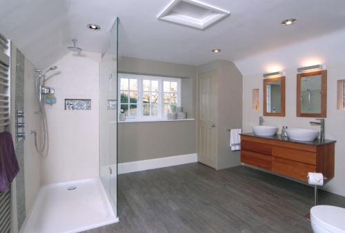 a bathroom with two sinks and a shower at Gardeners Cottage in Shipton under Wychwood