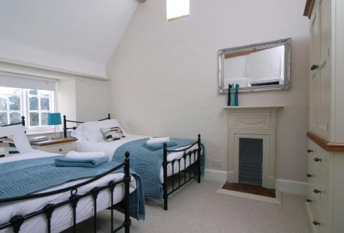 a bedroom with two beds and a fireplace at Gardeners Cottage in Shipton under Wychwood