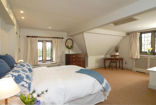 a bedroom with a bed and a table and windows at Apple Cottage in Snowshill