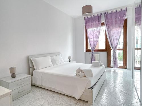 a white bedroom with a large bed with purple drapes at MYHOUSE INN PARADISO - Affitti Brevi Italia in Turin