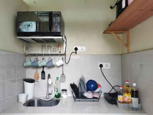 a kitchen counter with a sink and a microwave at Cheras-Miharja Homestay @Sunway Velocity in Kuala Lumpur
