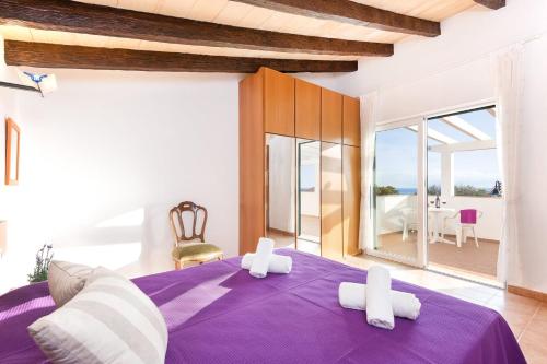 sypialnia z fioletowym łóżkiem i białymi ręcznikami w obiekcie Villa Beatrice by Villa Plus w mieście Binibeca