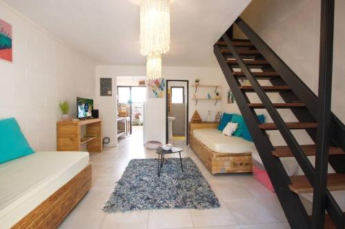 uma sala de estar com uma escada e um sofá em Kaz Lotis - à 50m de la plage Roches Noires em Saint-Gilles-les-Bains