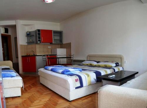 a room with two beds and a kitchen with red cabinets at City Center Apartments Ohrid in Ohrid