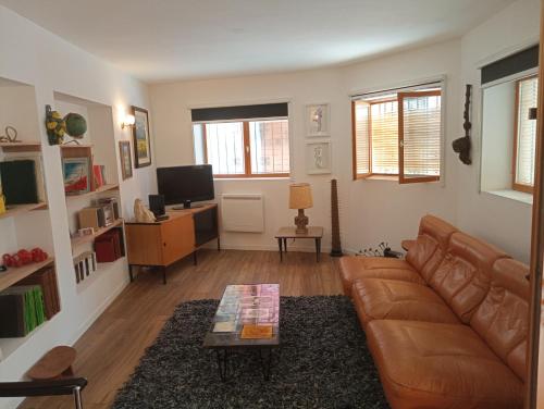 ein Wohnzimmer mit einem braunen Ledersofa und einem Tisch in der Unterkunft Thuir: superbe appartement in Thuir