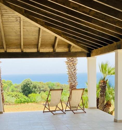 two chairs sitting on a porch with the ocean in the background at Villa Mancosta in Marinella di Selinunte