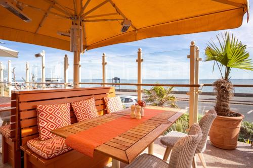 a table and chairs on a patio with an umbrella at Roslin Beach Hotel in Southend-on-Sea