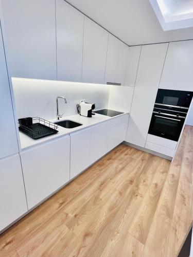 a kitchen with white cabinets and a wooden floor at Loft City Center Viana in Viana do Castelo