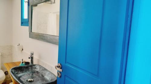 a bathroom with a sink and a blue door at Tirquaz View in Serifos Chora
