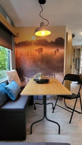 a living room with a table and a couch at Familychalet De Schaapskooi, 6-persons, big private garden, dogs aloud in Westergeest