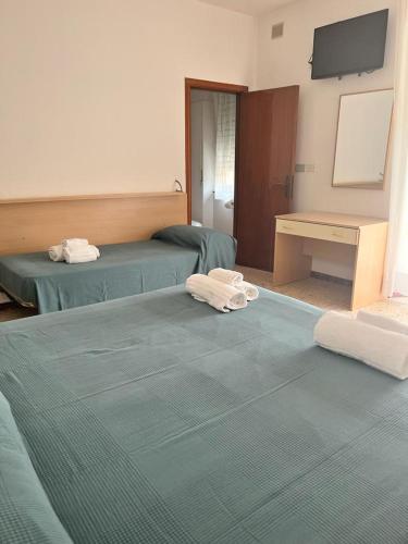 two beds in a hotel room with towels on them at Ubika Hotel in Porto San Giorgio