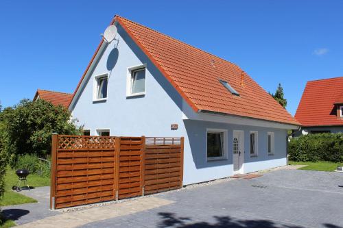 a house with an orange roof and a wooden fence at Haus Wiekend - Fewo Strandkrabbe in Wiek auf Rügen 