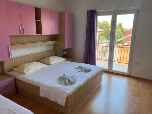 a bedroom with a bed with pink cabinets and a window at Apartmani Kacola in Tučepi
