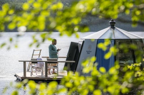 a man sitting at a table on a dock on the water at Sju Sjöar in Hyltenäs