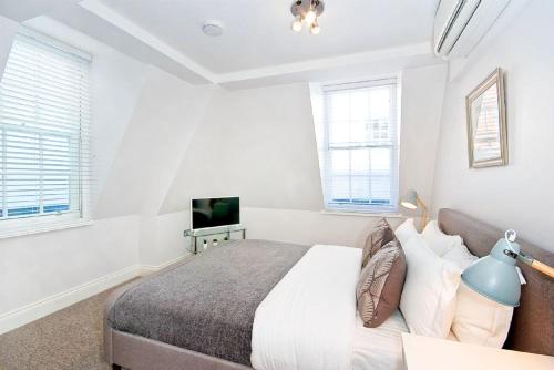a white bedroom with a bed and a tv at Eldon Chambers Flat 1 by City Living London in London