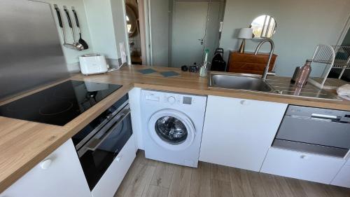 a kitchen with a washing machine and a sink at Vue sur rade appartement élégant vaste climatisé étage élevé ascenseur proche parking et toutes commodités au cœur du Toulon historique in Toulon