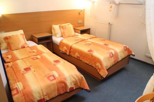 a hotel room with two beds with orange sheets at Pension Janka Kdyně in Kdyně
