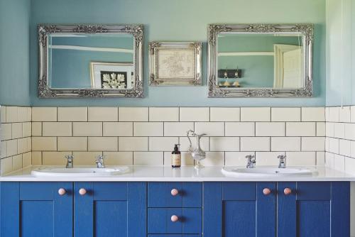 a bathroom with two sinks and two mirrors at Equestrian Manor in Upton upon Severn
