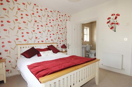 a bedroom with a bed with red pillows and a floral wallpaper at slieve rushen in Derrylin