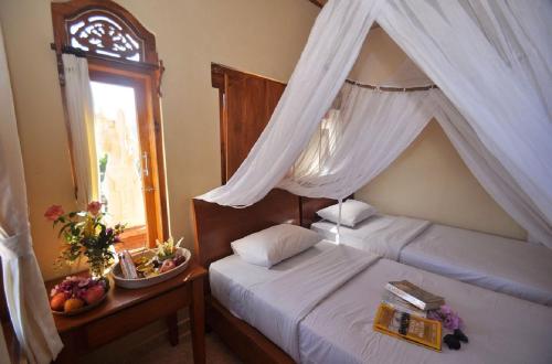Un dormitorio con una cama con dosel y una ventana. en Meme Surung Guesthouse, en Munduk