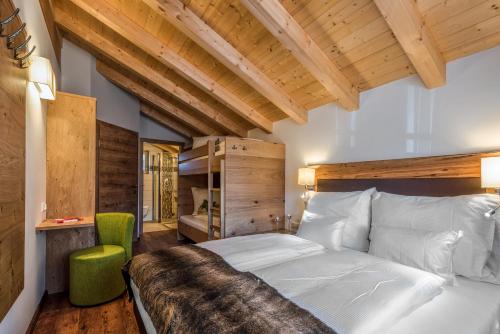 a bedroom with a white bed and a green chair at Chalets AurAlpin in Kleinarl