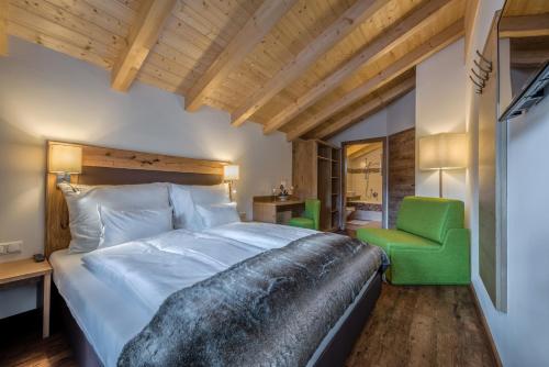 a bedroom with a large bed and a green chair at Chalets AurAlpin in Kleinarl