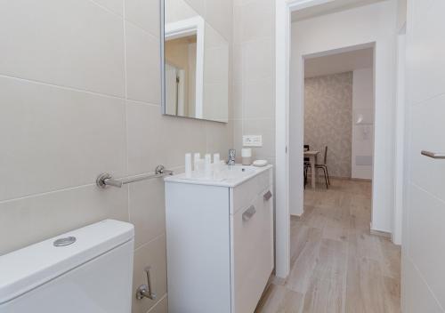 ein weißes Badezimmer mit einem Waschbecken und einem Spiegel in der Unterkunft Moderno apartamento urbano en barrio histórico 2ºI in Santa Cruz de Tenerife