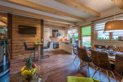 a kitchen and living room with wooden walls and a dining room at Chalets AurAlpin in Kleinarl