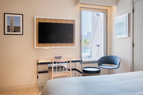 a hotel room with a bed and a television on the wall at El Vicenç de la Mar - Adults Only - Over 12 in Pollença