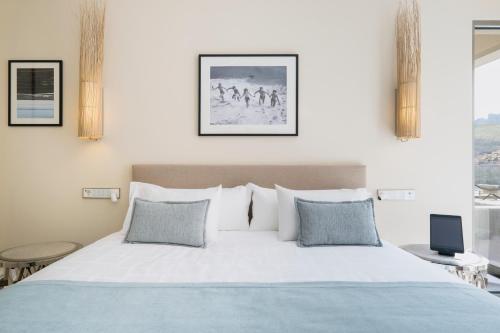 a bedroom with a large white bed with blue pillows at El Vicenç de la Mar - Adults Only - Over 12 in Pollença