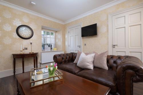 a living room with a brown leather couch at The Old Schoolhouse of Warren Lodge Boutique Cottages in Dromod