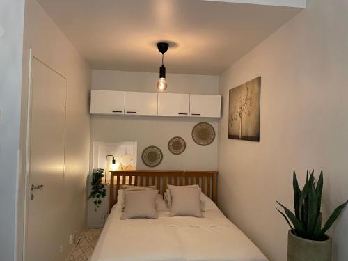 a bedroom with a bed with white sheets and a plant at Lux home II in Tampere