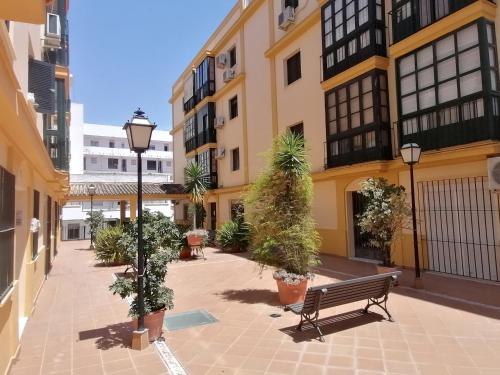 un patio con banco y macetas de árboles y edificios en Apartamento Tres Carabelas, AC, Wifi, Parking, en Sanlúcar de Barrameda