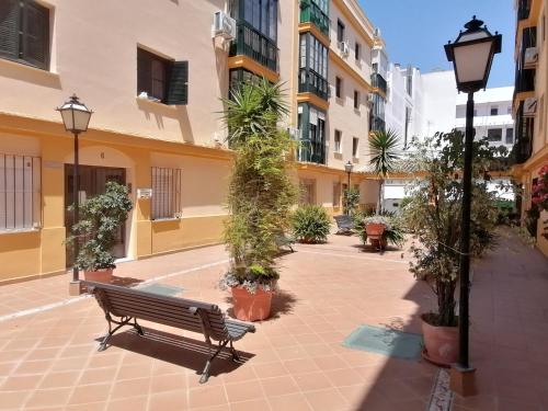un banco en un patio con árboles y edificios en Apartamento Tres Carabelas, AC, Wifi, Parking, en Sanlúcar de Barrameda