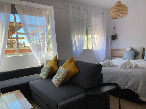 ein Wohnzimmer mit einem Sofa und einem Bett in der Unterkunft Loft en PLENO CENTRO in Sanlúcar de Barrameda