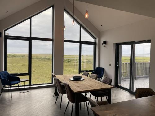 a dining room with a table and chairs and large windows at Machrie View in Port Ellen