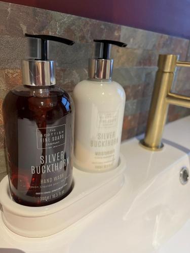 two bottles of soap sitting on a bathroom sink at Machrie View in Port Ellen
