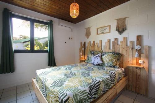 ein Schlafzimmer mit einem Bett in einem Zimmer mit einem Fenster in der Unterkunft Kaz Nomia - à 50m de la plage Roches Noires in Saint-Gilles-les-Bains