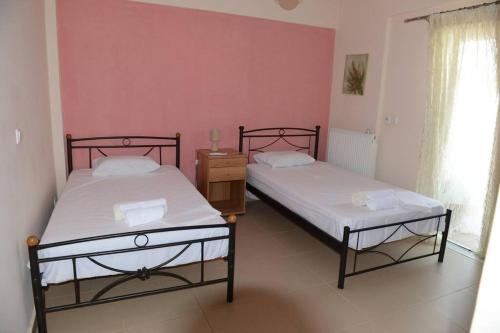 two beds in a room with pink walls at Ducky House in Preveza