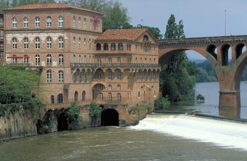 a large brick building with a bridge over a river at Mercure Albi Rives du Tarn in Albi