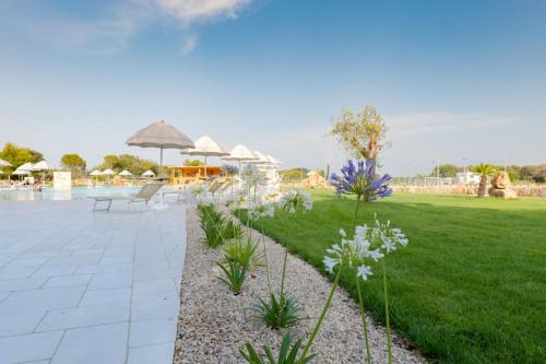 a garden with white flowers and a swimming pool at Tenuta Ferraro Gallipoli in Gallipoli