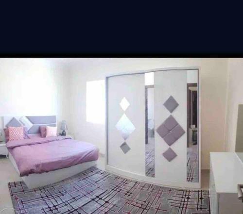 a bedroom with a purple bed and a mirror at Beautiful Flat By The Beach Salalah in Salalah