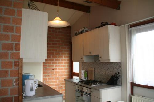 a kitchen with white cabinets and a brick wall at Rekerlanden 173 in Schoorldam