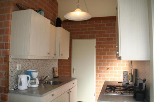 a kitchen with white cabinets and a brick wall at Rekerlanden 173 in Schoorldam