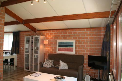 sala de estar con sofá y pared de ladrillo en Rekerlanden 173 en Schoorldam