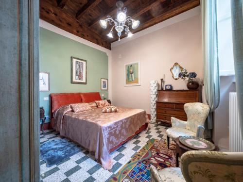 a bedroom with a bed and a chair and a chandelier at LUXURY - Elegante appartamento nel cuore di Lucca in Lucca